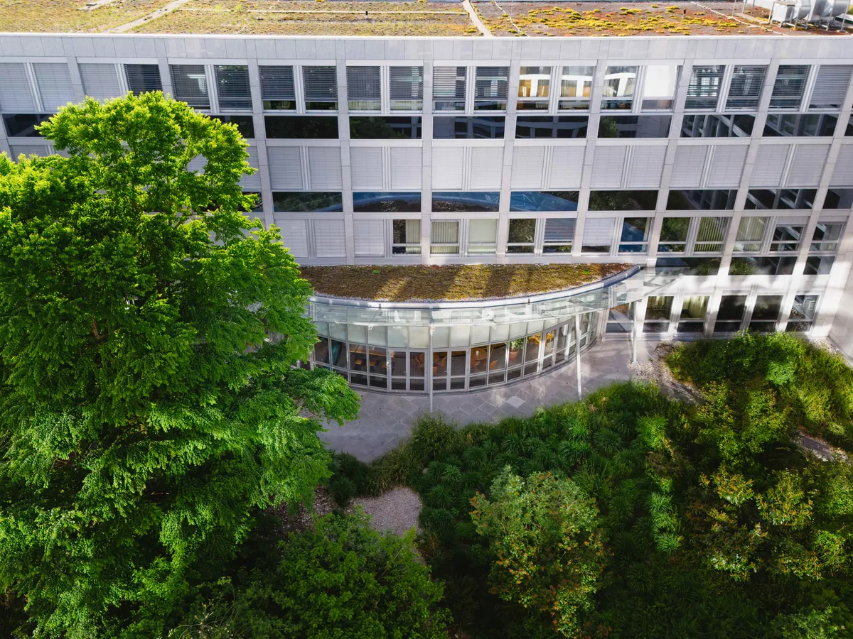 Begrünter Innenhof mit geschwungenem Glasanbau, München